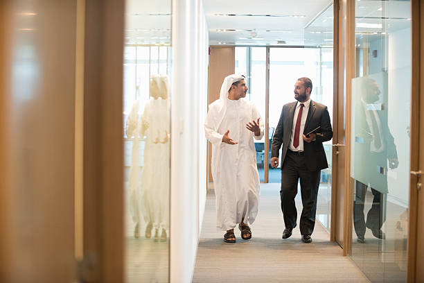 Two businessmen discussing opportunities while walking down a corridor in RAKEZ Free Zone office complex.